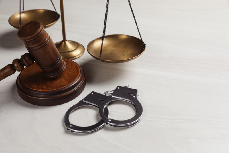 Judge's Gavel, Handcuffs, Scales On White Wooden, Background